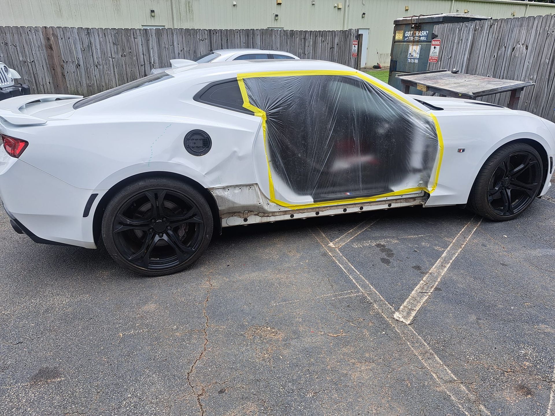 A white car with the door open is parked in a parking lot.