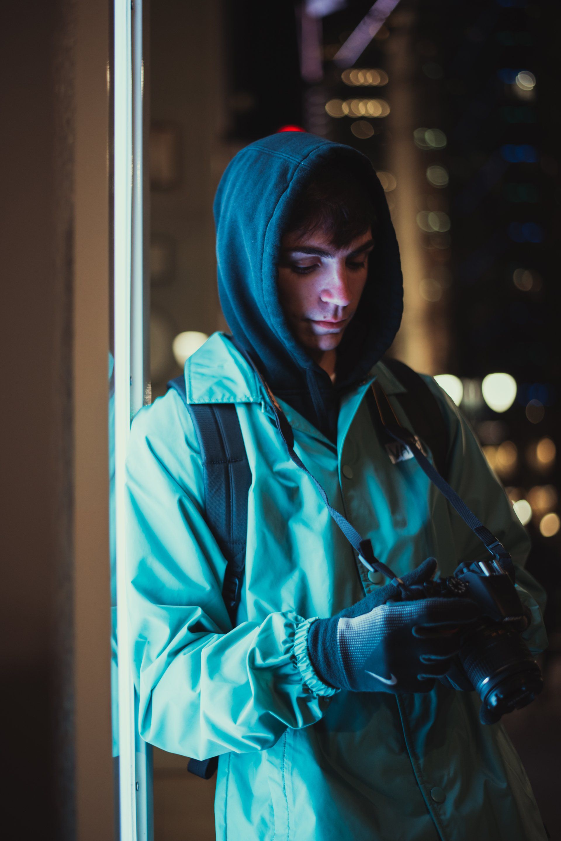 A man in a hooded jacket is taking a picture with a camera.