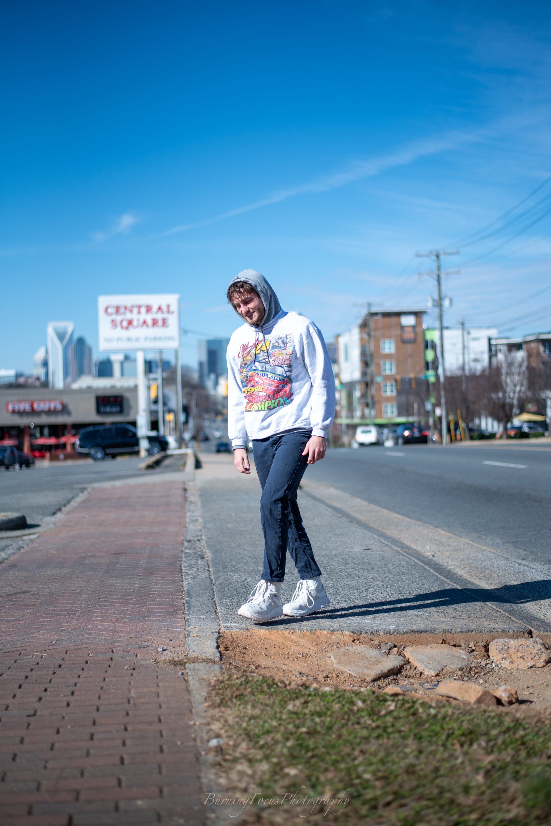 A man is standing on a sidewalk next to a street.
