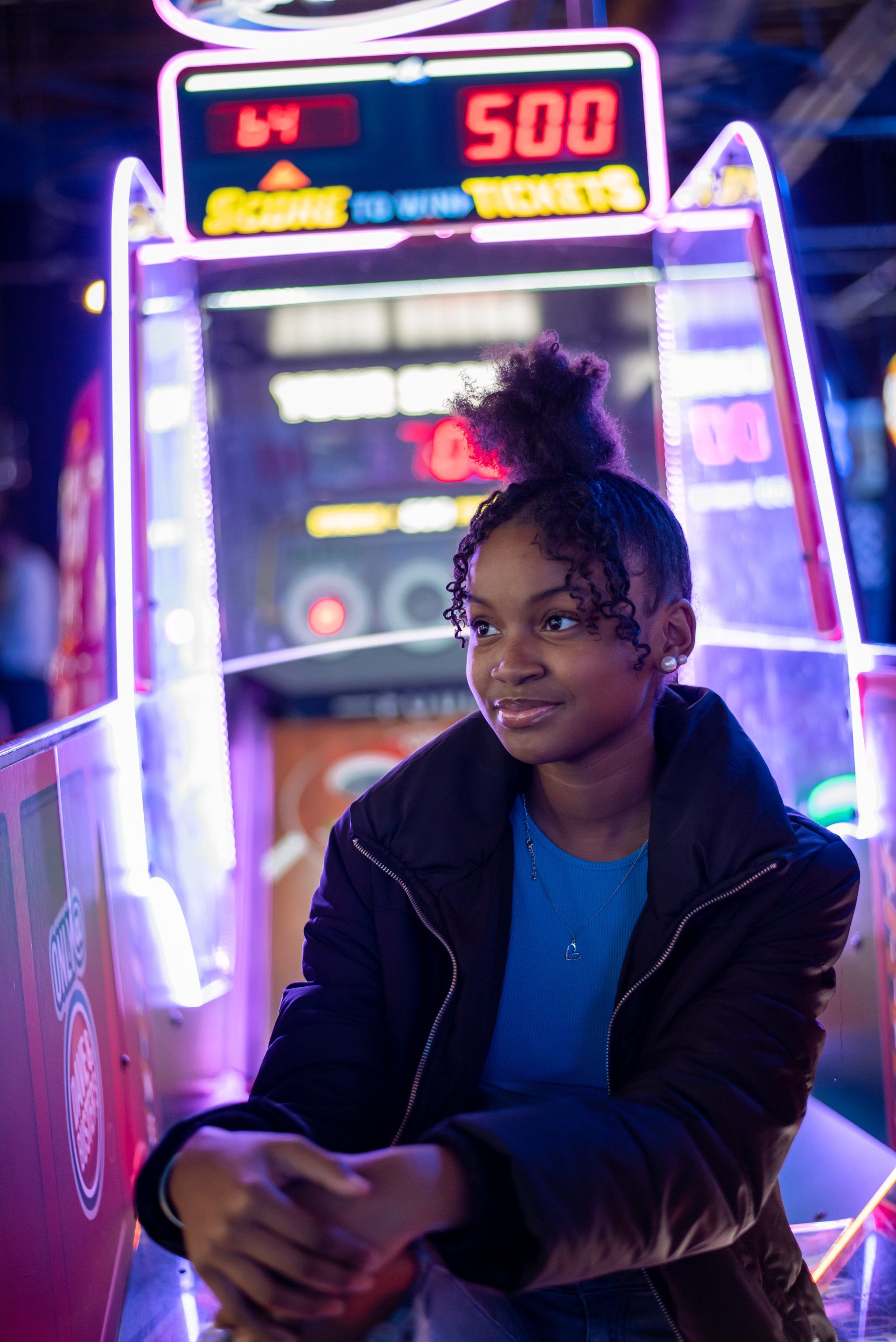 A young girl is sitting in front of an arcade machine.