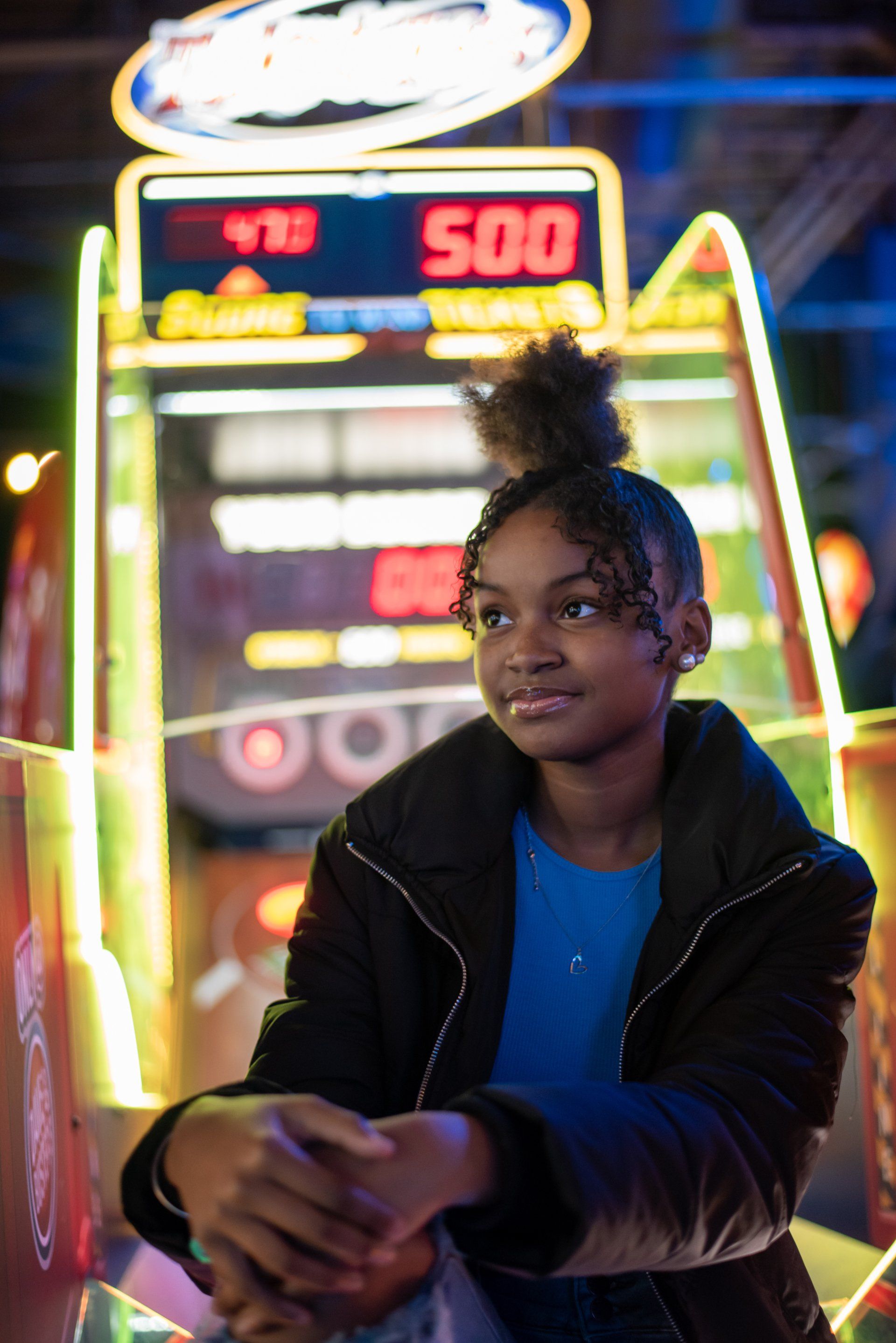 A young girl is sitting in front of an arcade machine.