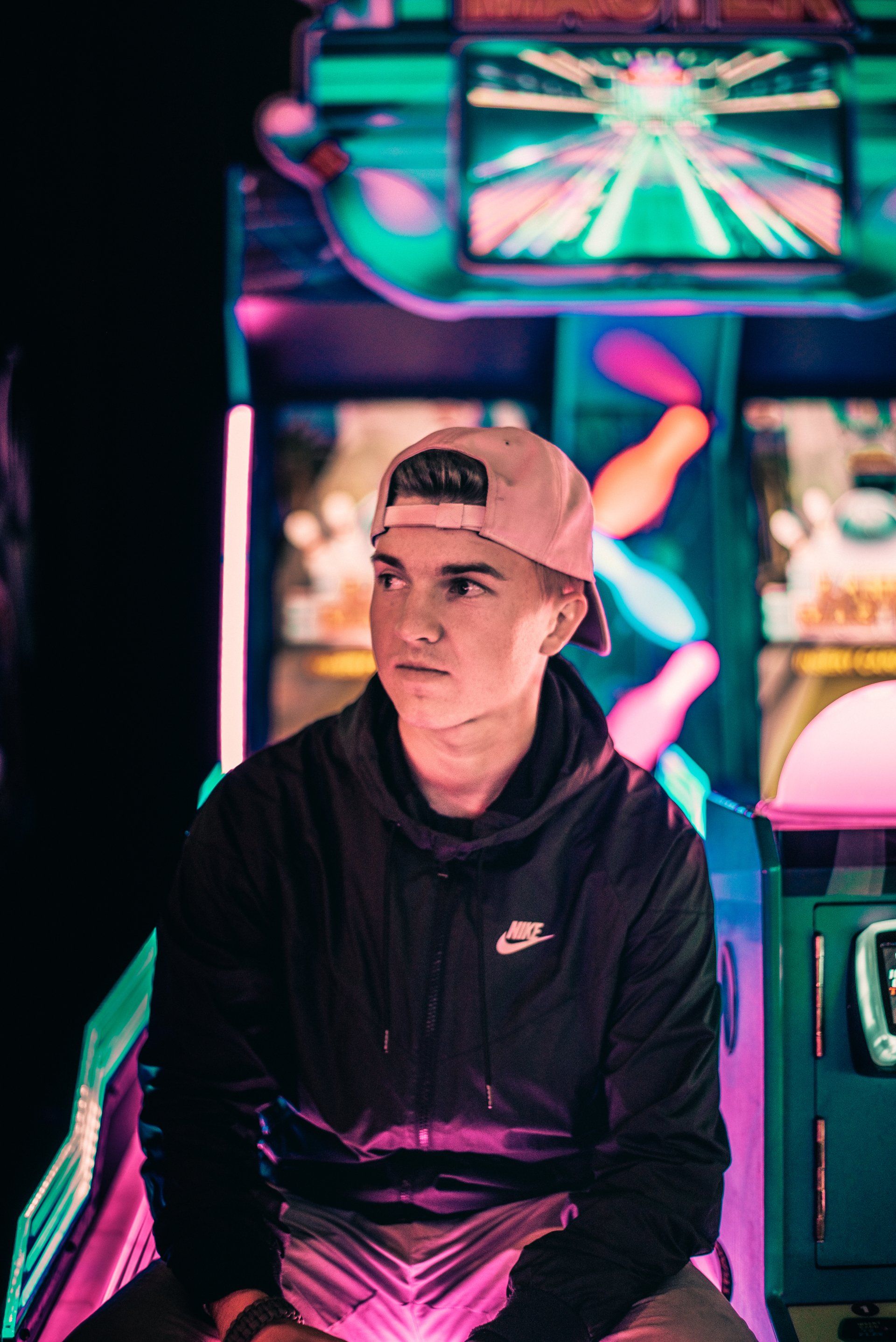A young man is sitting in front of an arcade machine.