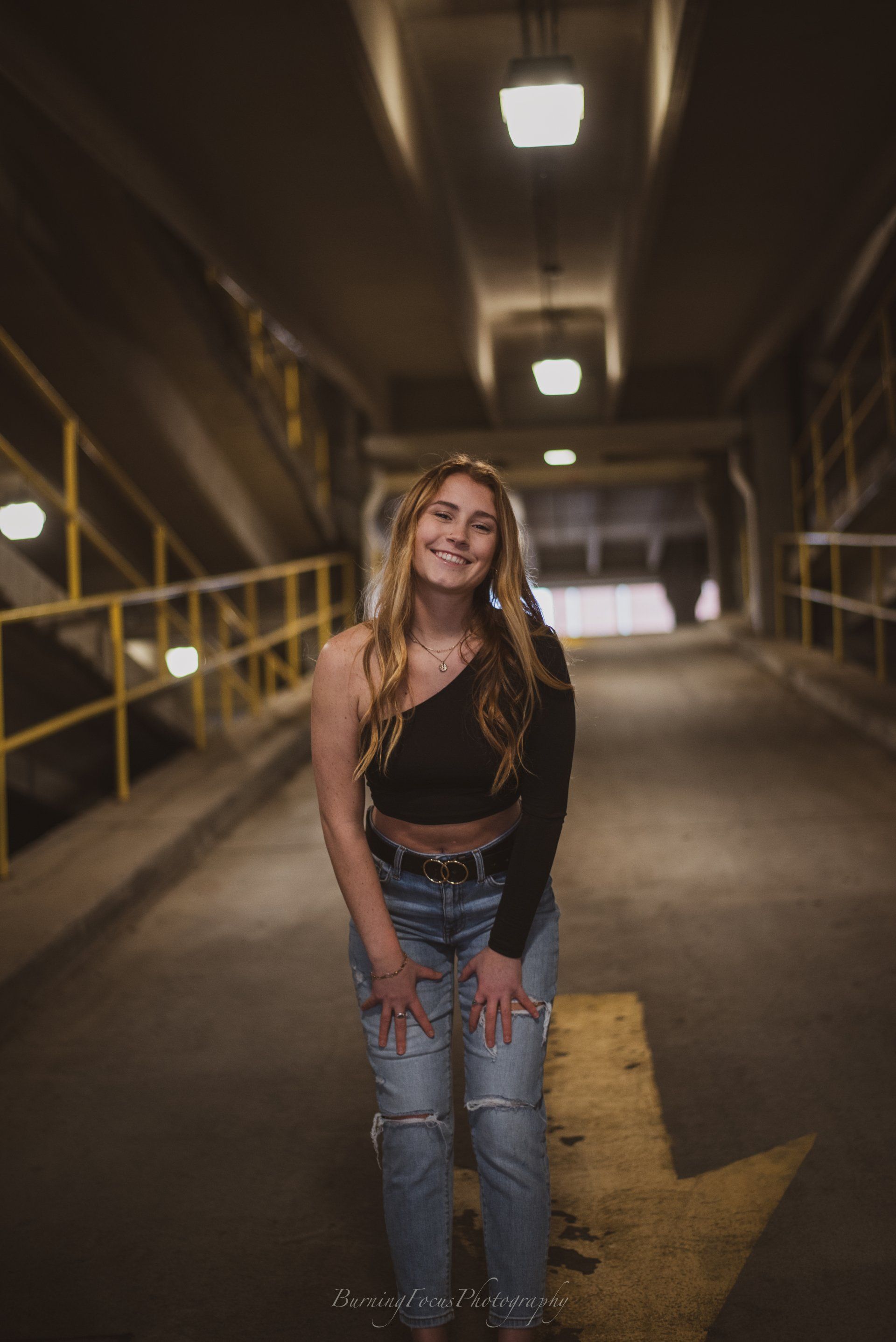 A woman is posing for a picture in a parking garage.