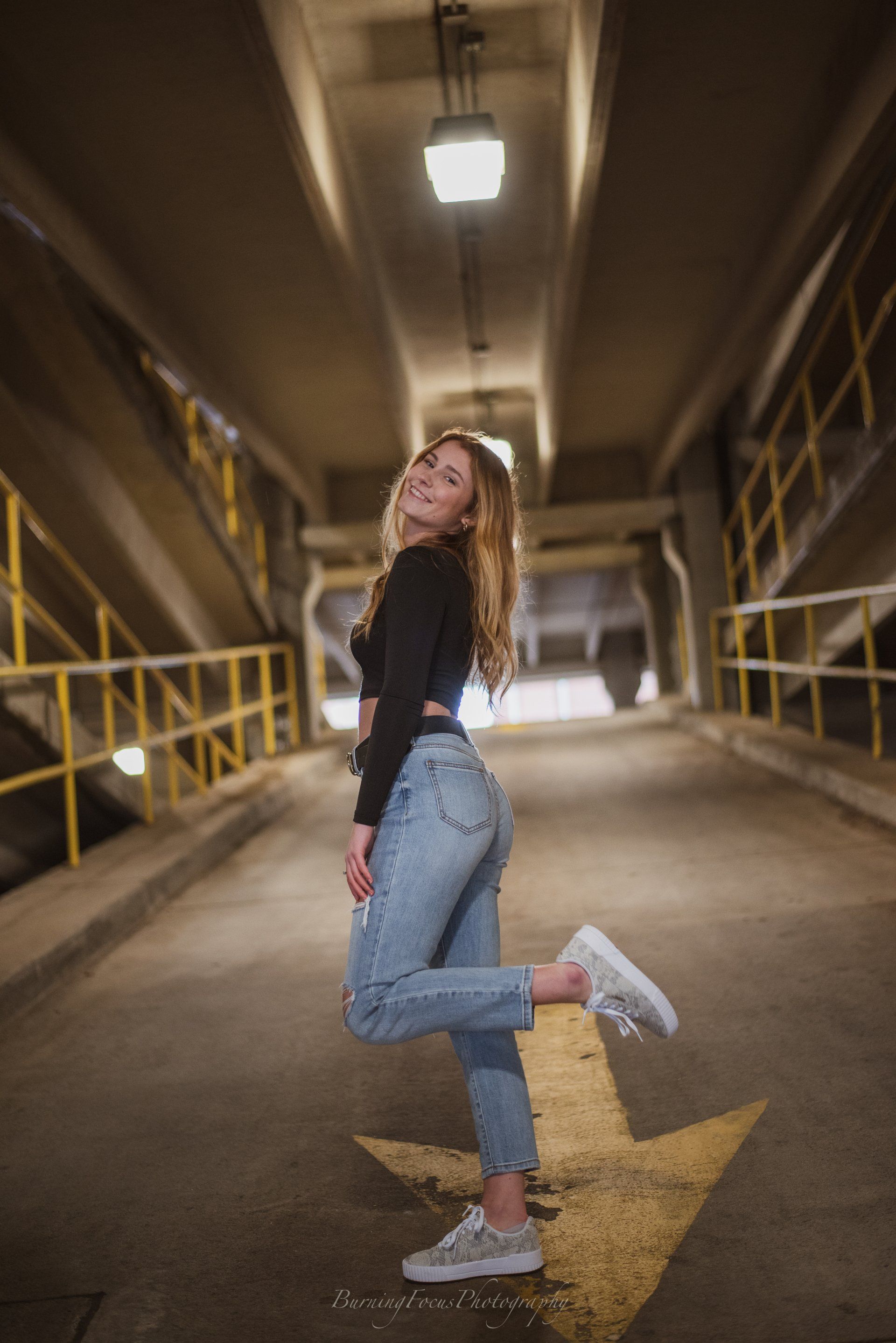 A woman is posing for a picture in a parking garage.