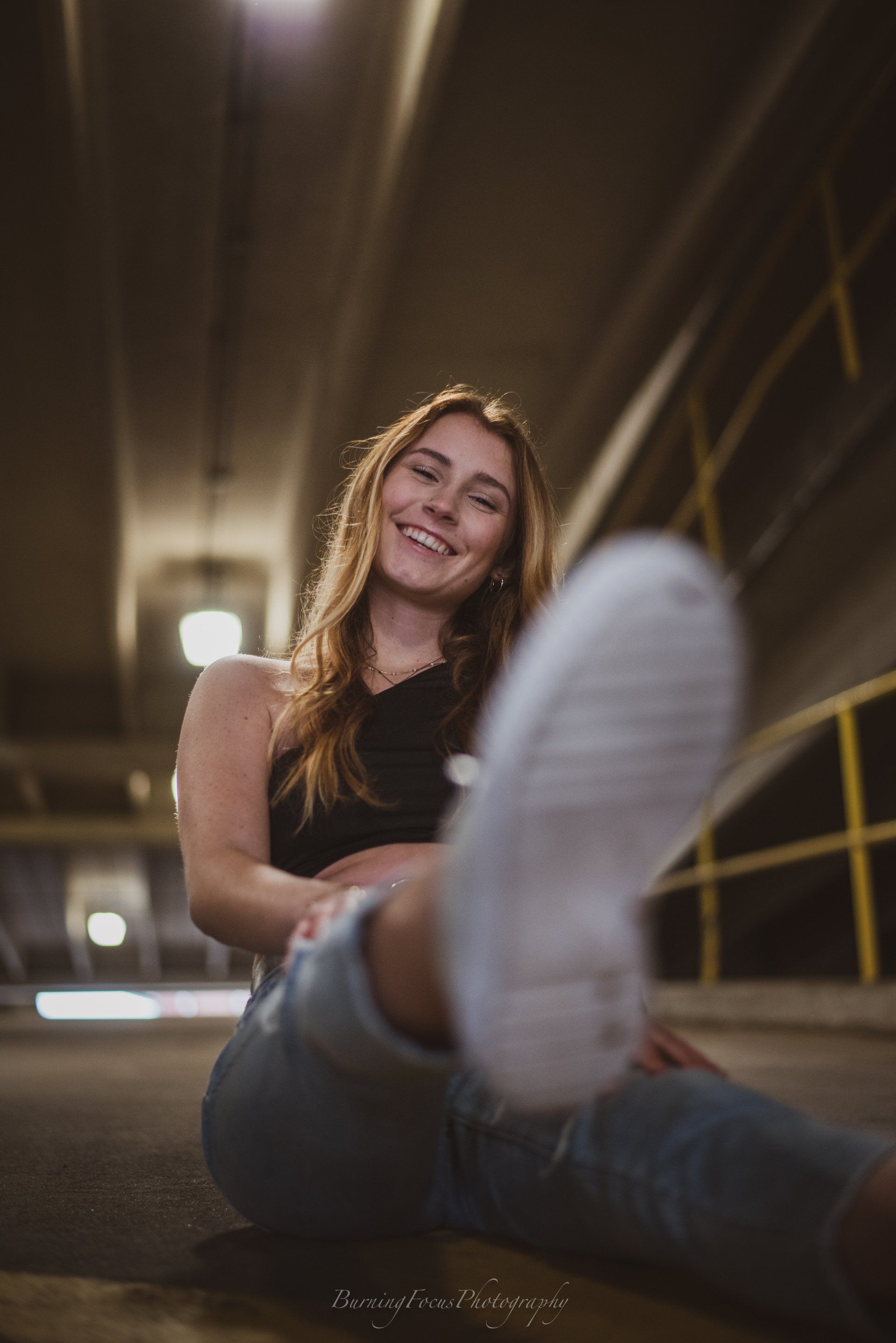 A woman is sitting on the ground with her foot in the air.