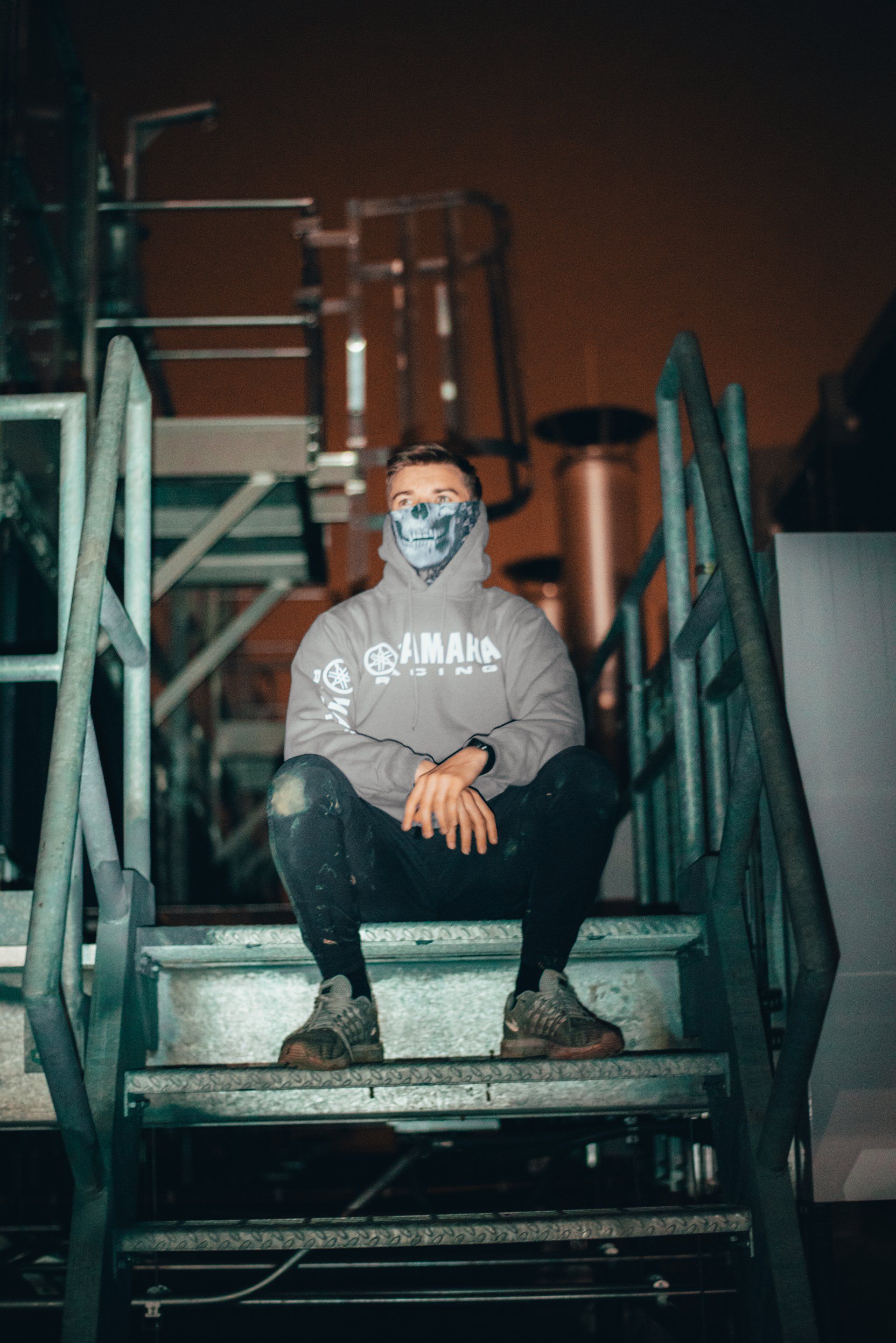 A man wearing a mask is sitting on a set of stairs.