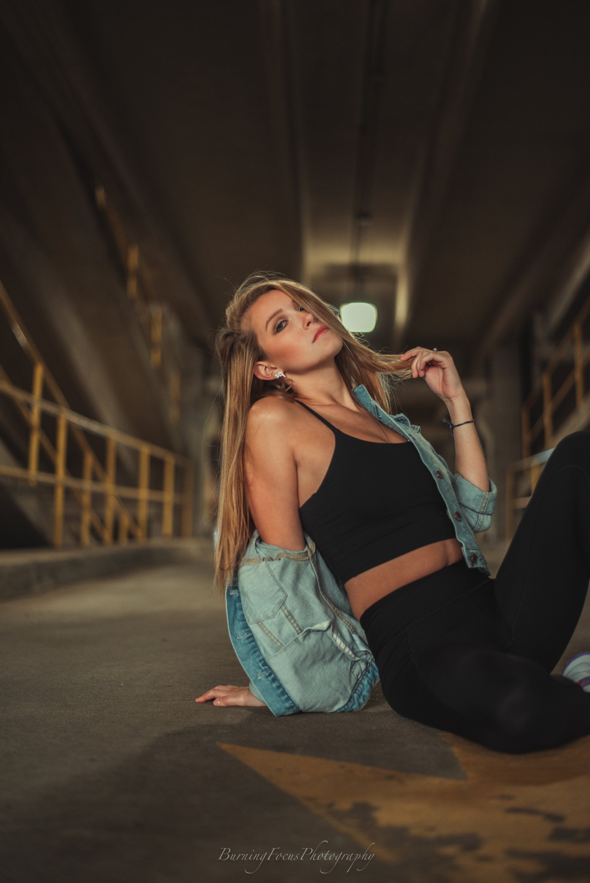 A woman is sitting on the ground in a dark hallway.