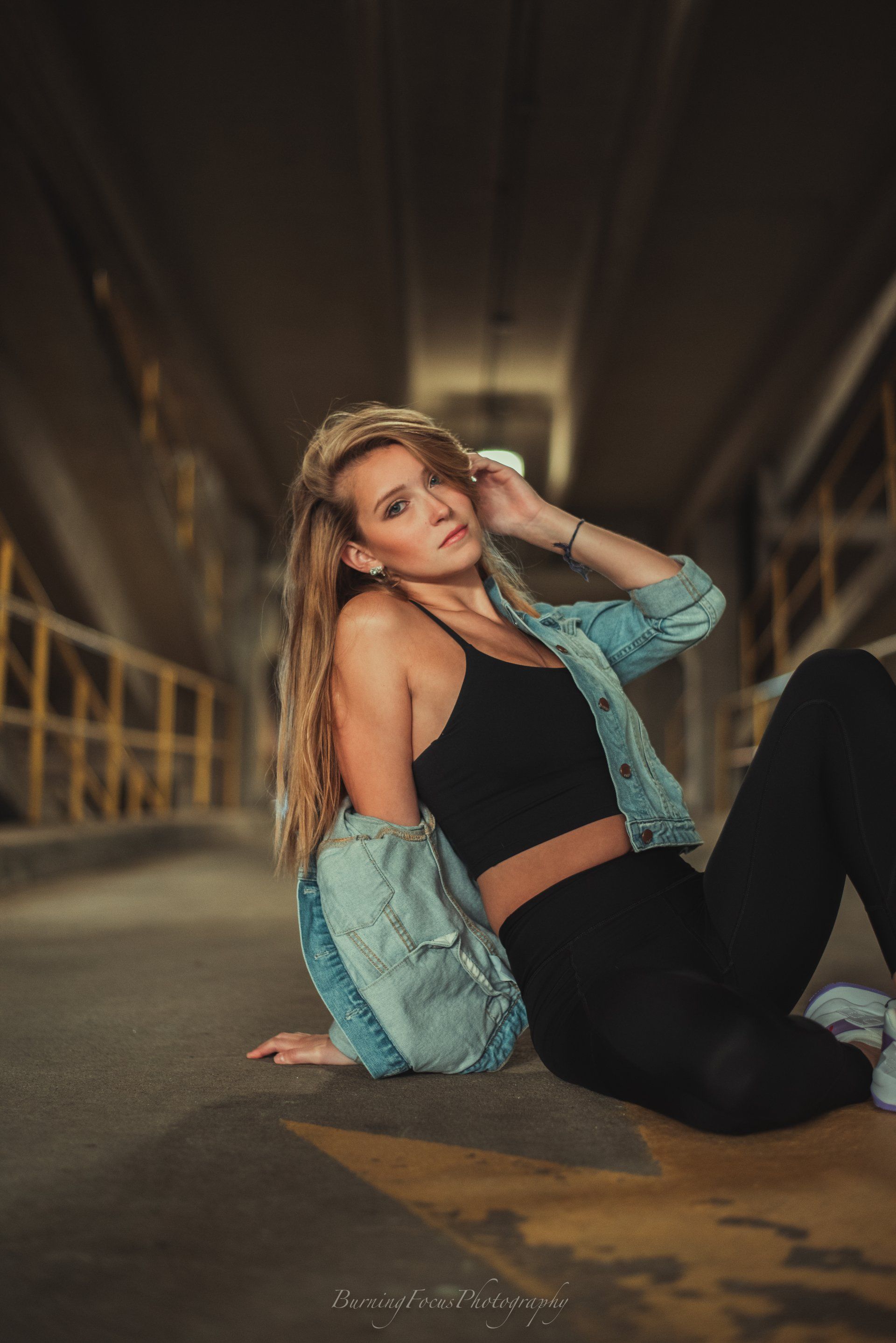 A woman is sitting on the ground in a dark hallway.