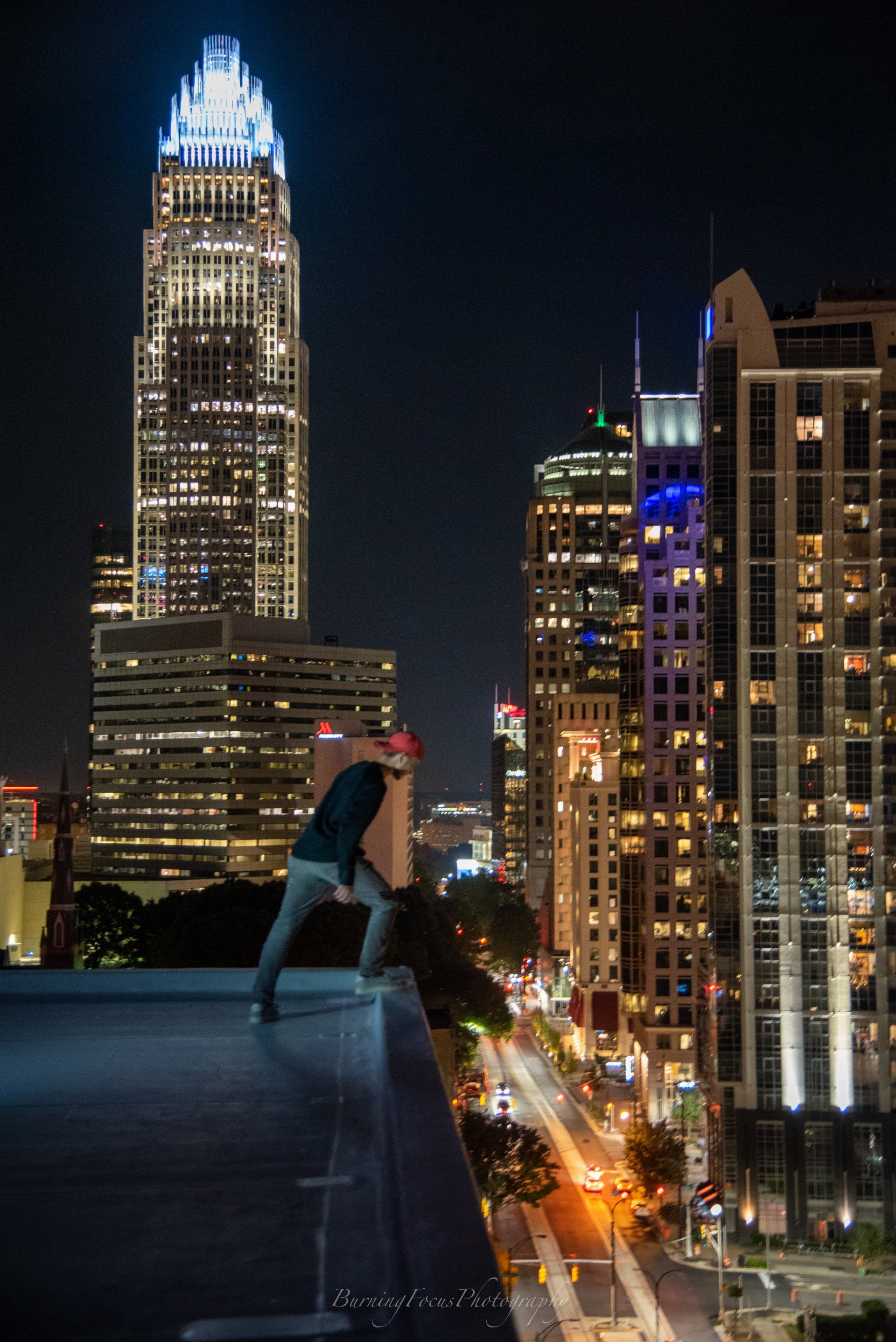 A man is standing on top of a tall building at night.