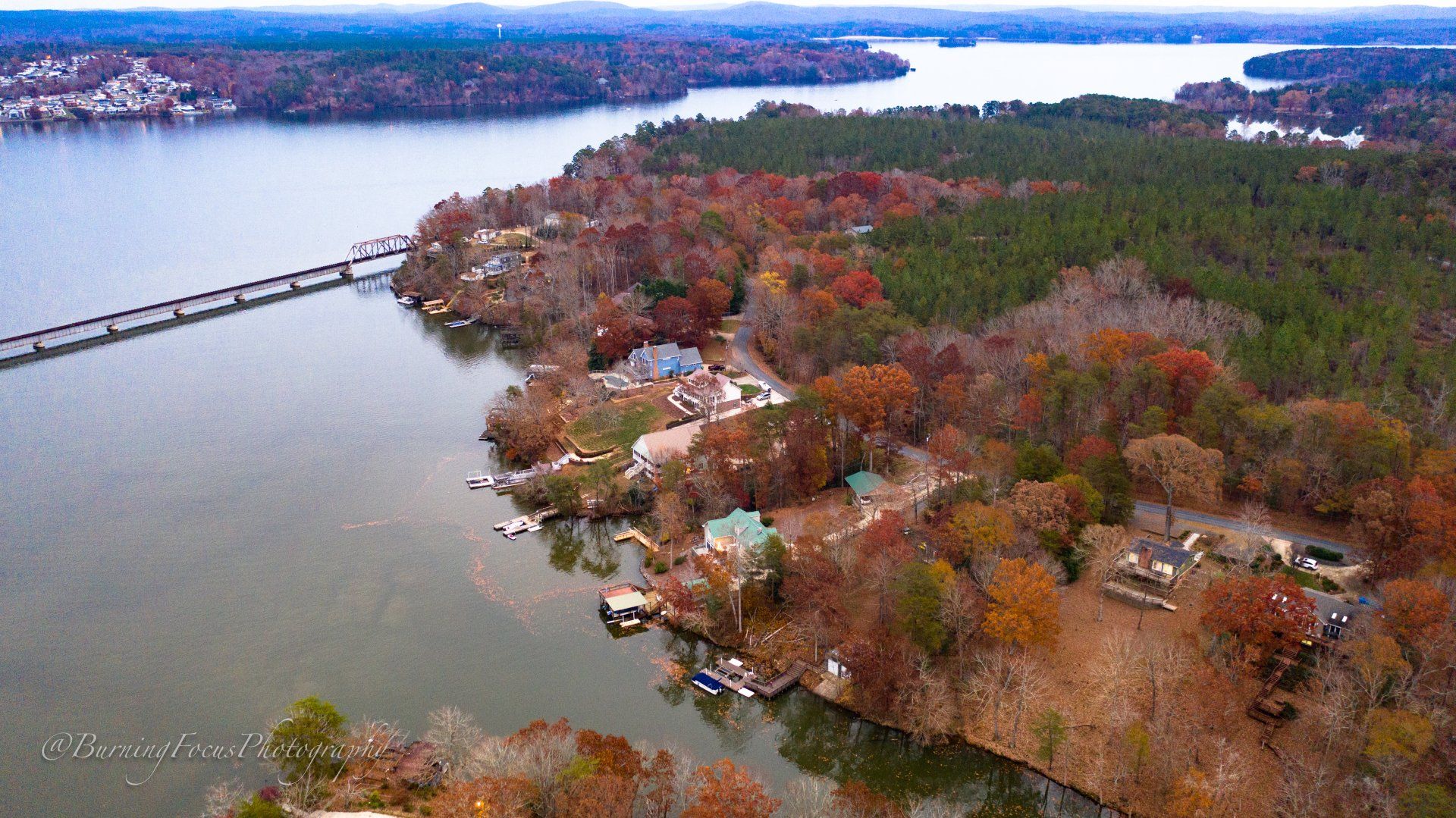 An aerial view of a lake surrounded by trees and a bridge.