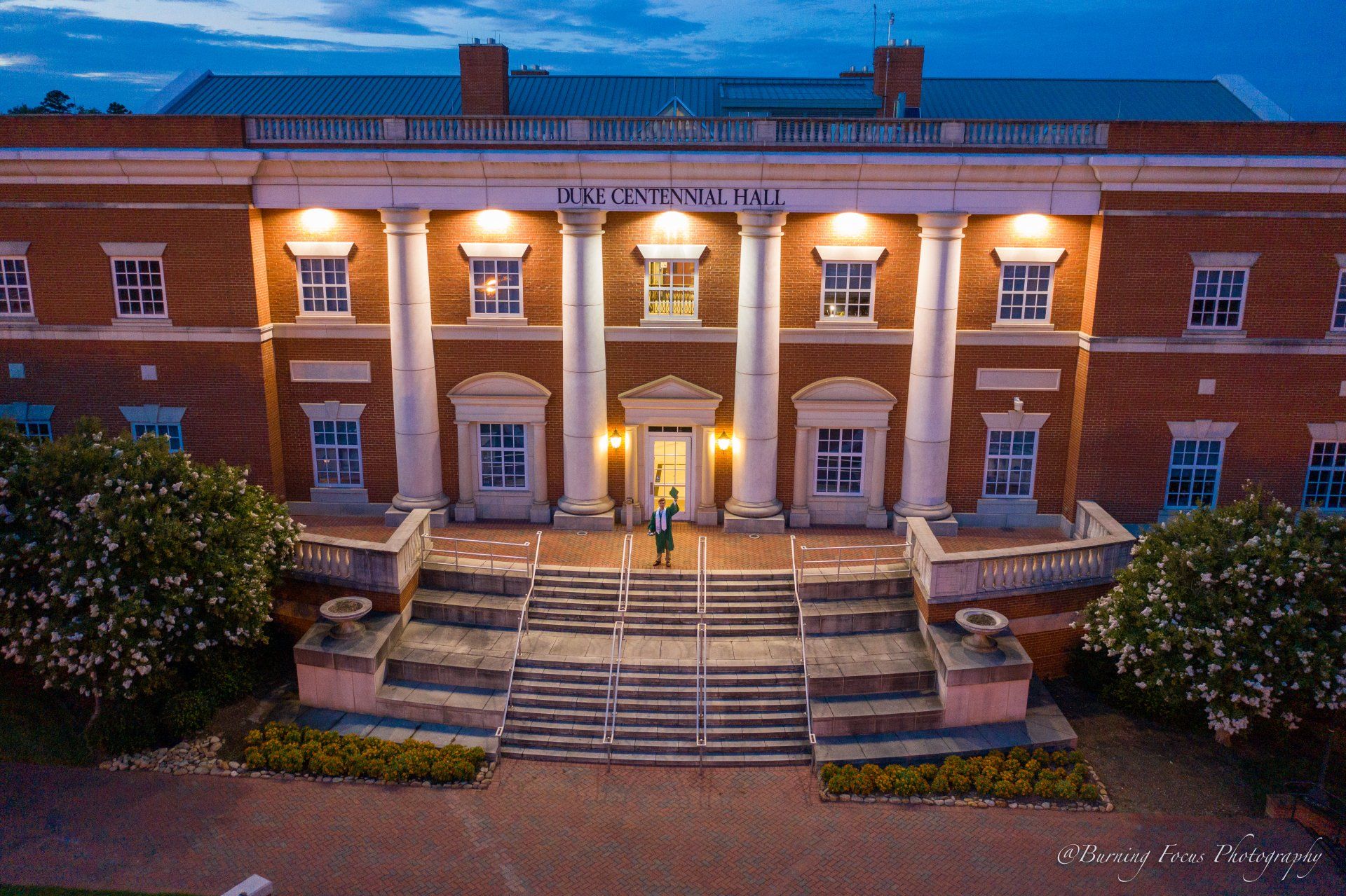An aerial view of a large brick building with a man standing in front of it.