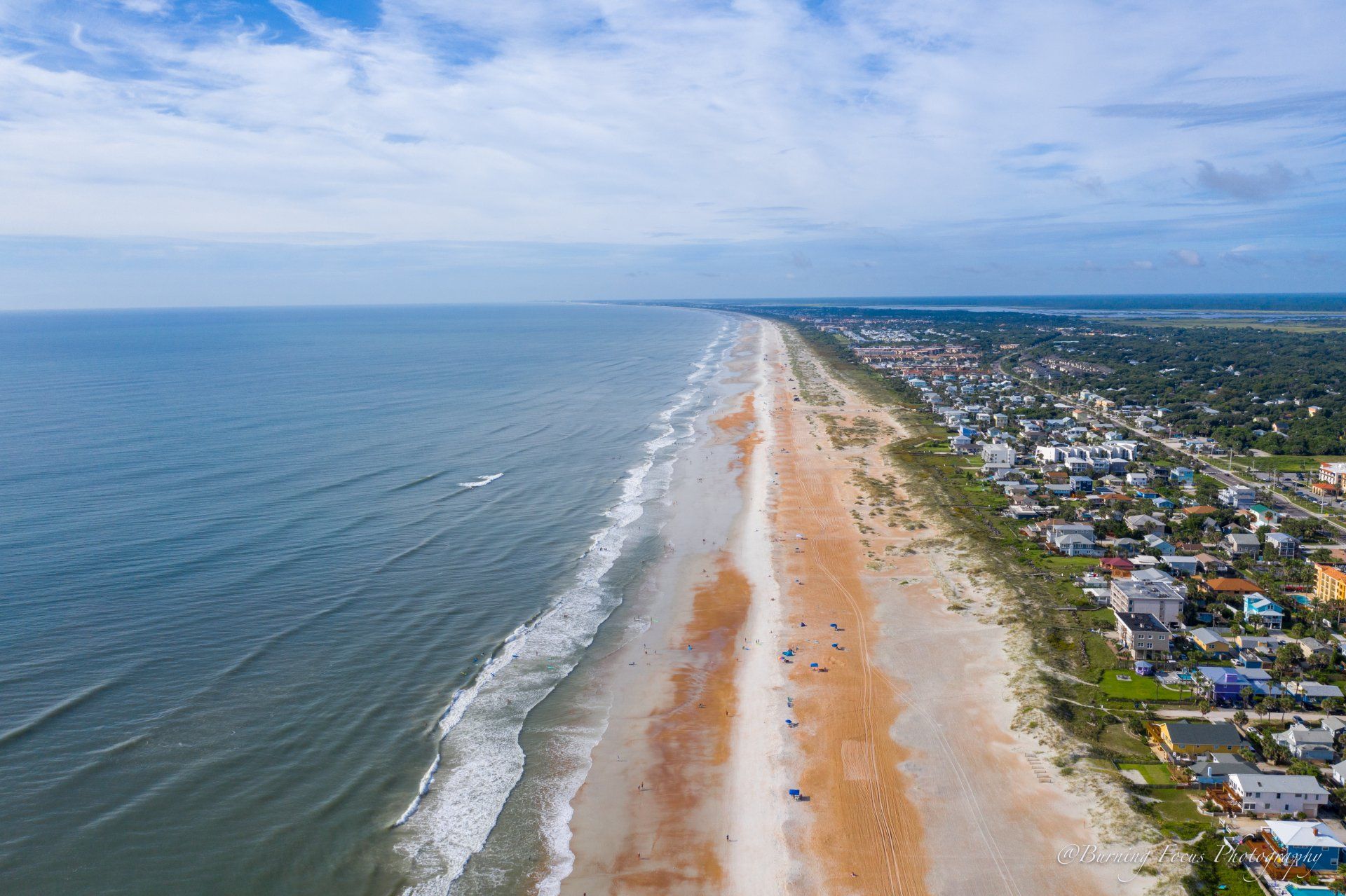 An aerial view of a long sandy beach next to the ocean.
