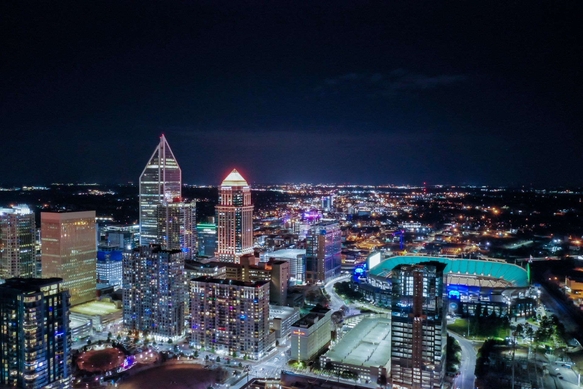 An aerial view of a city at night with a stadium in the foreground.