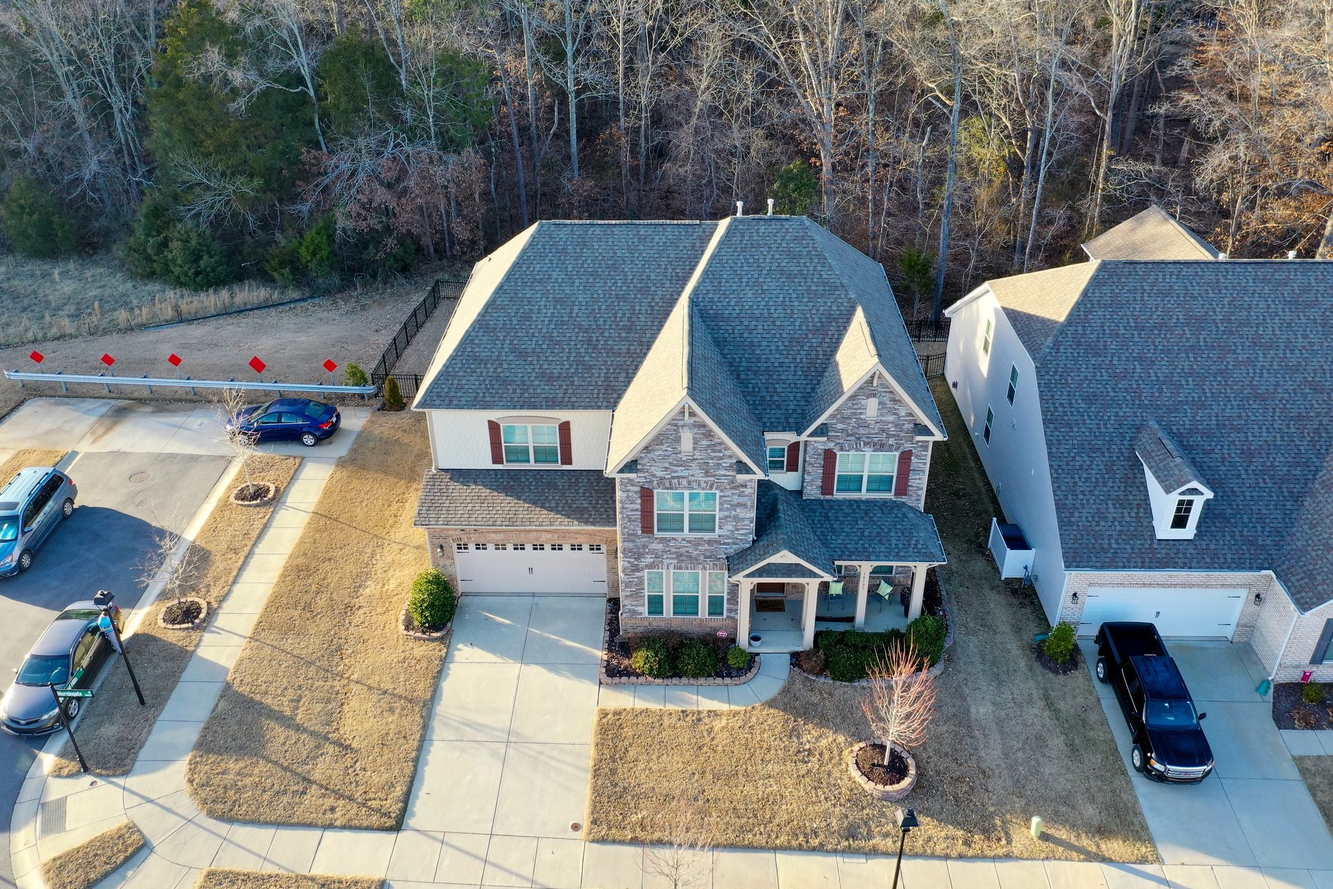 An aerial view of a house in a residential area with cars parked in front of it.