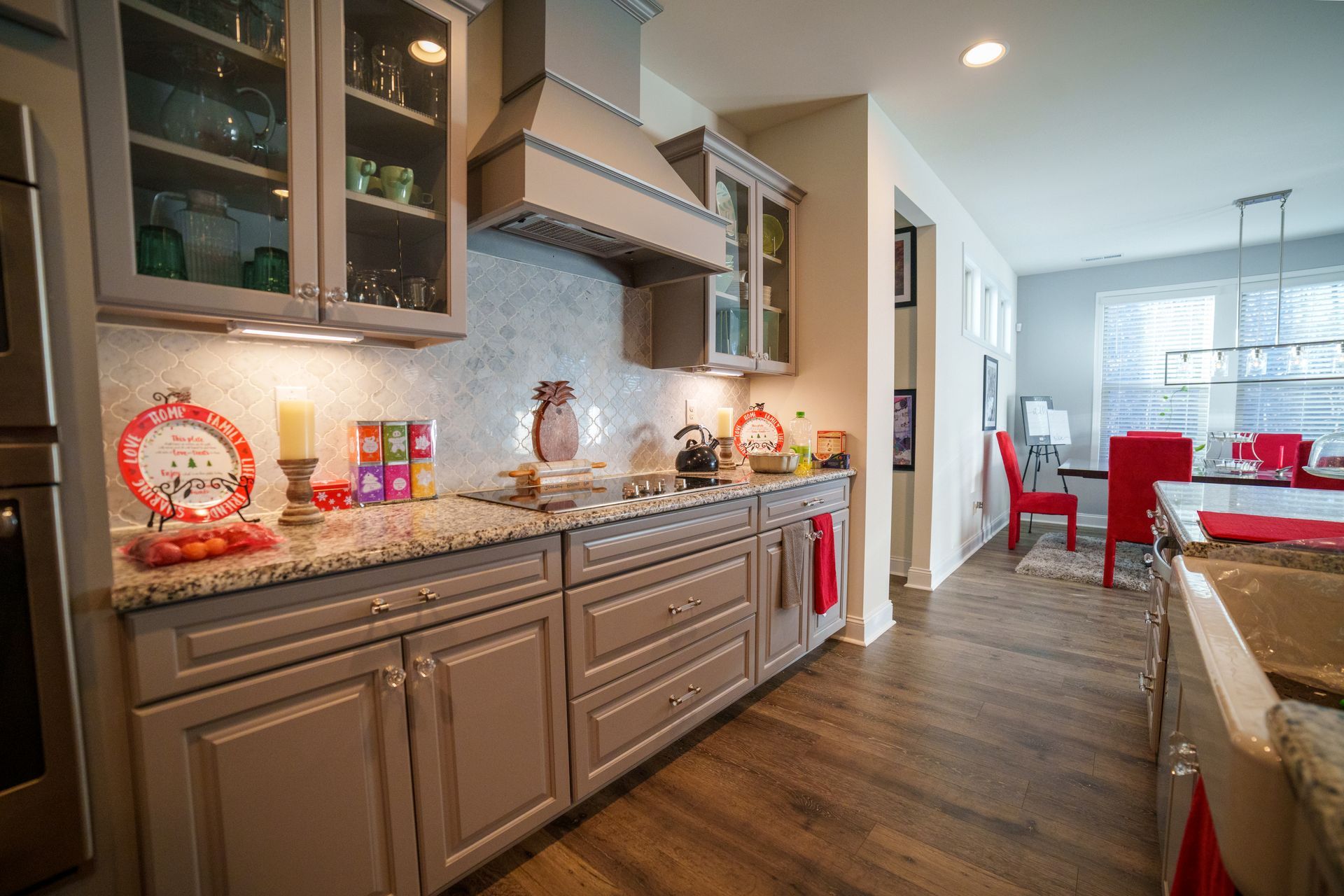 A kitchen with gray cabinets , granite counter tops , and stainless steel appliances.