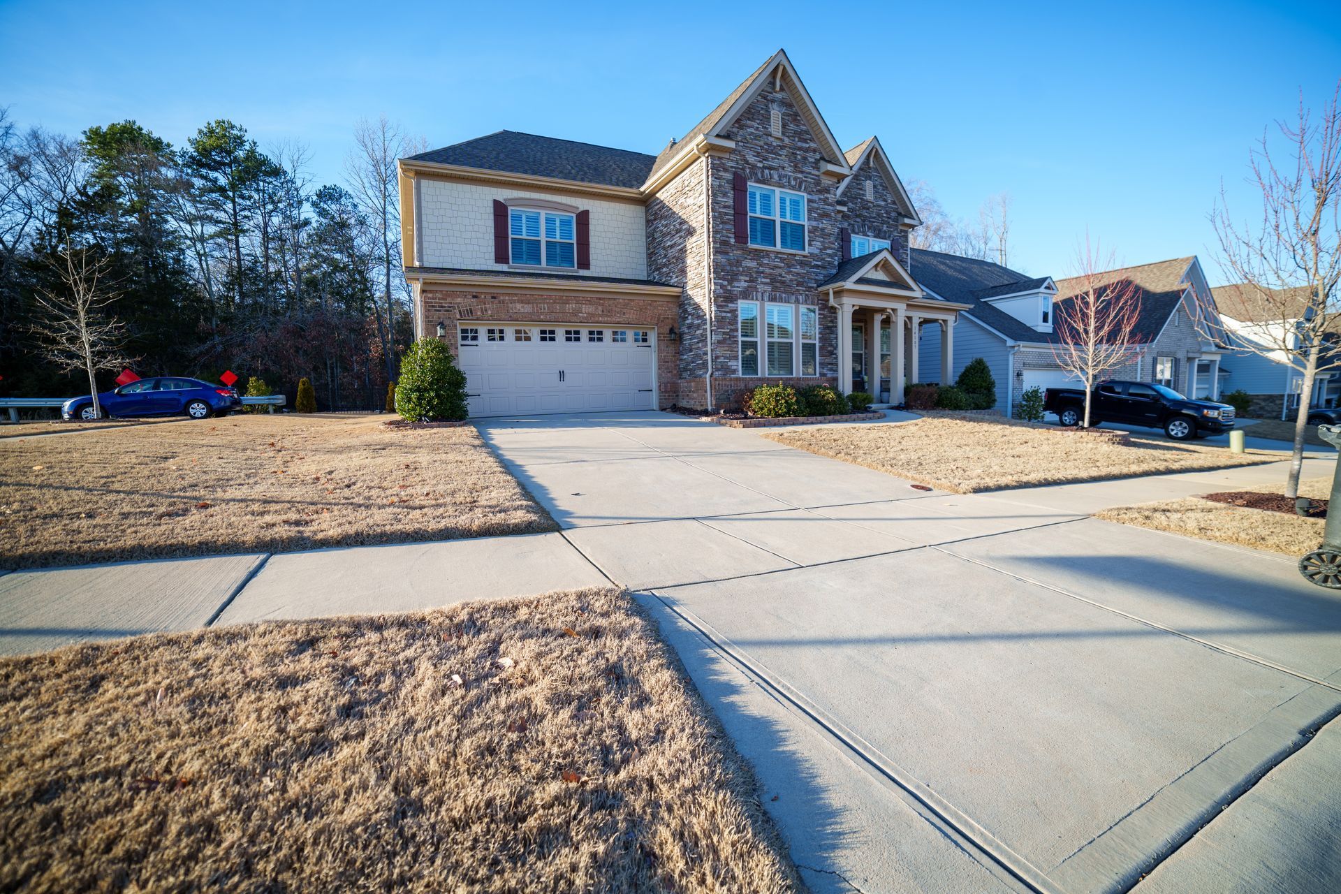 A large brick house with a concrete driveway in front of it