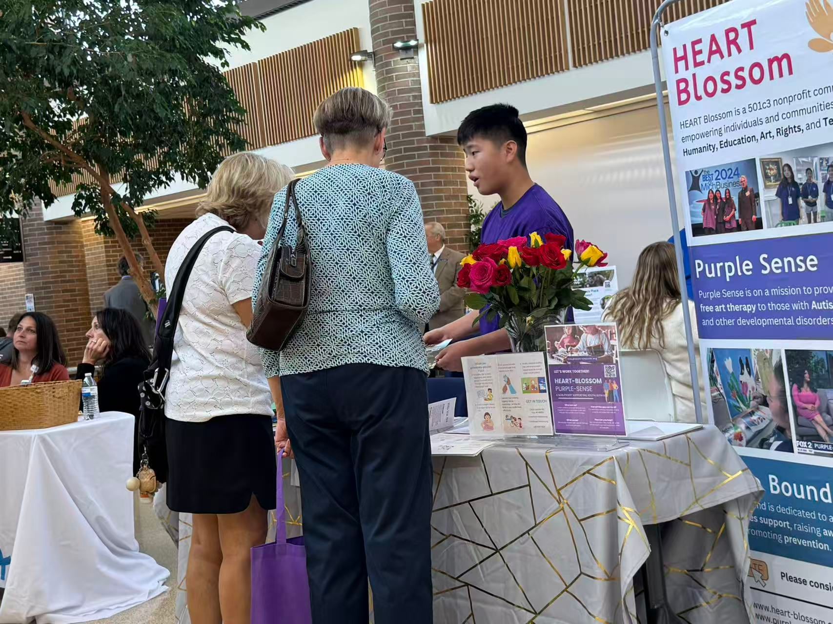 Man at a table with two women. A sign says 