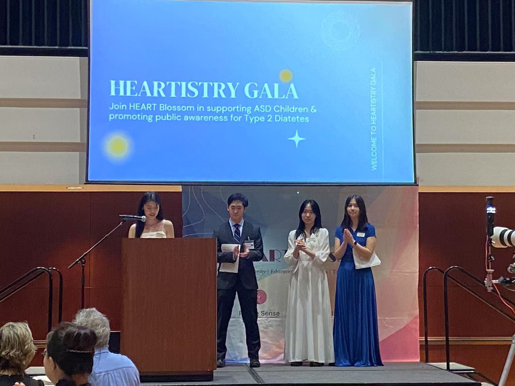 People on stage at gala: speaker, presenters, sign promoting event for type 2 diabetes awareness.