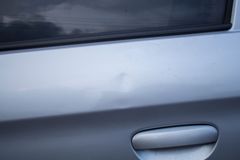 A close up of a car door with a scratch on it.