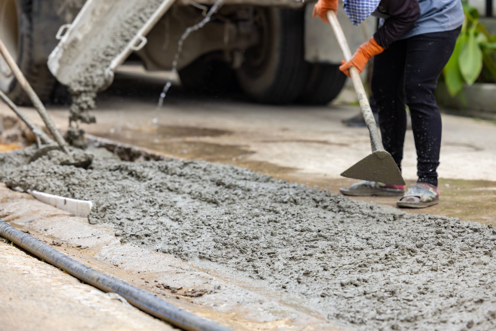 Workers spreading fresh cement from a truck during professional ready-mix concrete services. Workers spreading fresh cement from a truck during professional ready-mix concrete services.