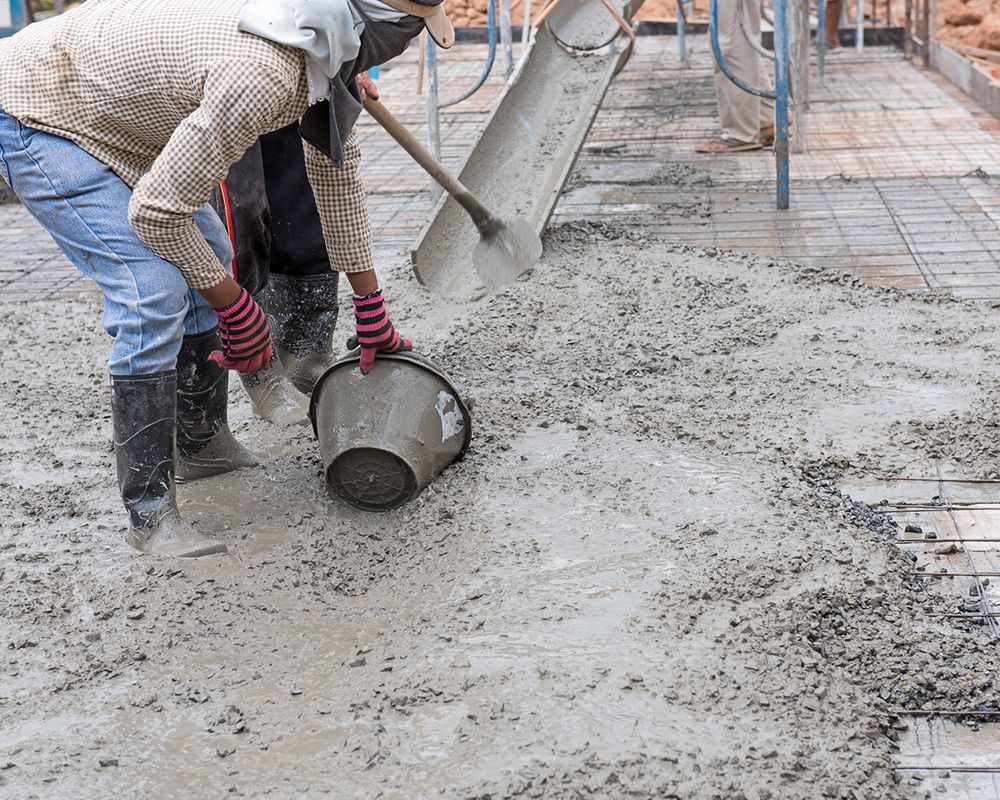 Construction workers spreading fresh concrete mix in Carolina Beach, NC, from Southport Concrete Corp. for house building.