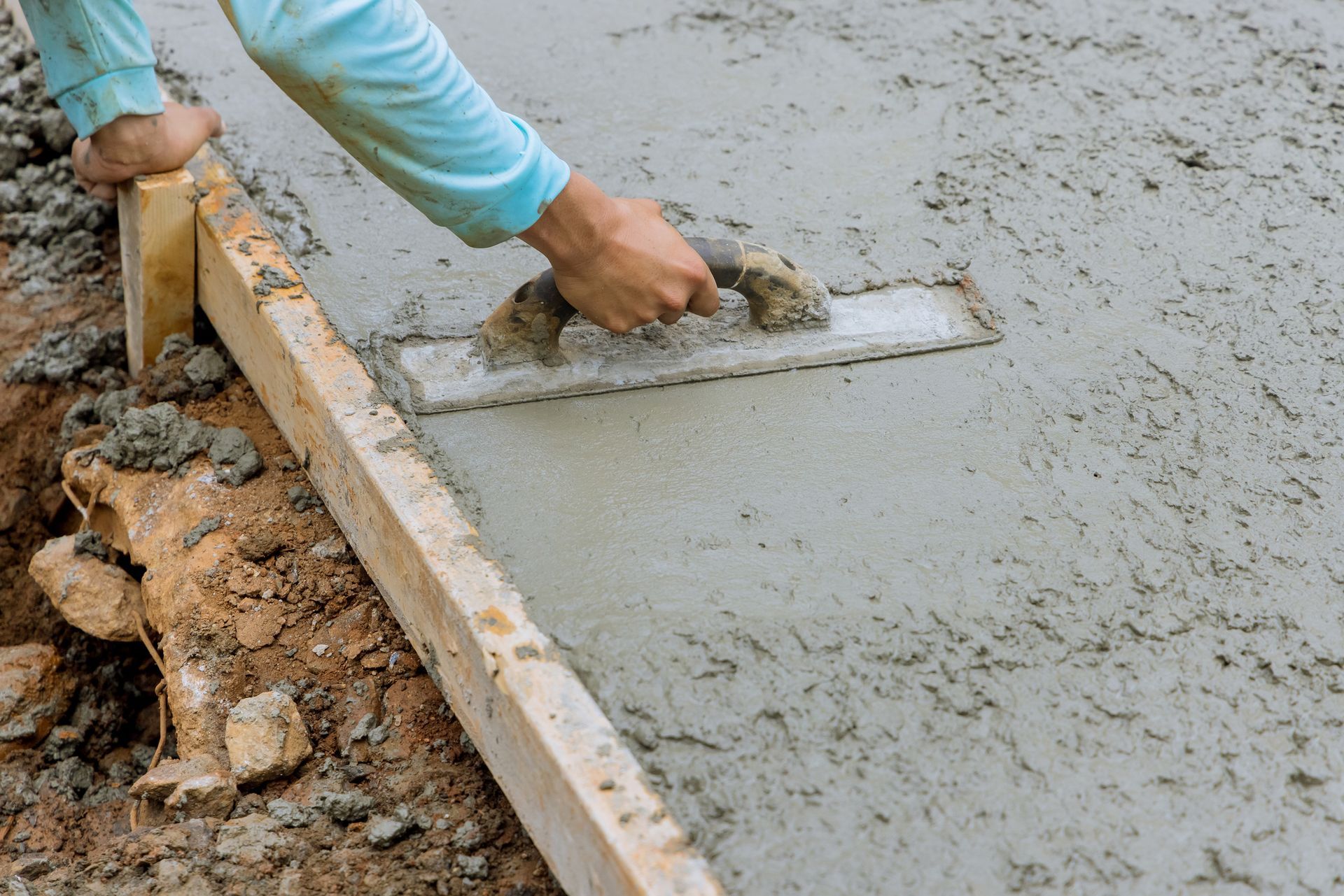 Man using a trowel to smooth ready-mix concrete for professional services on site.