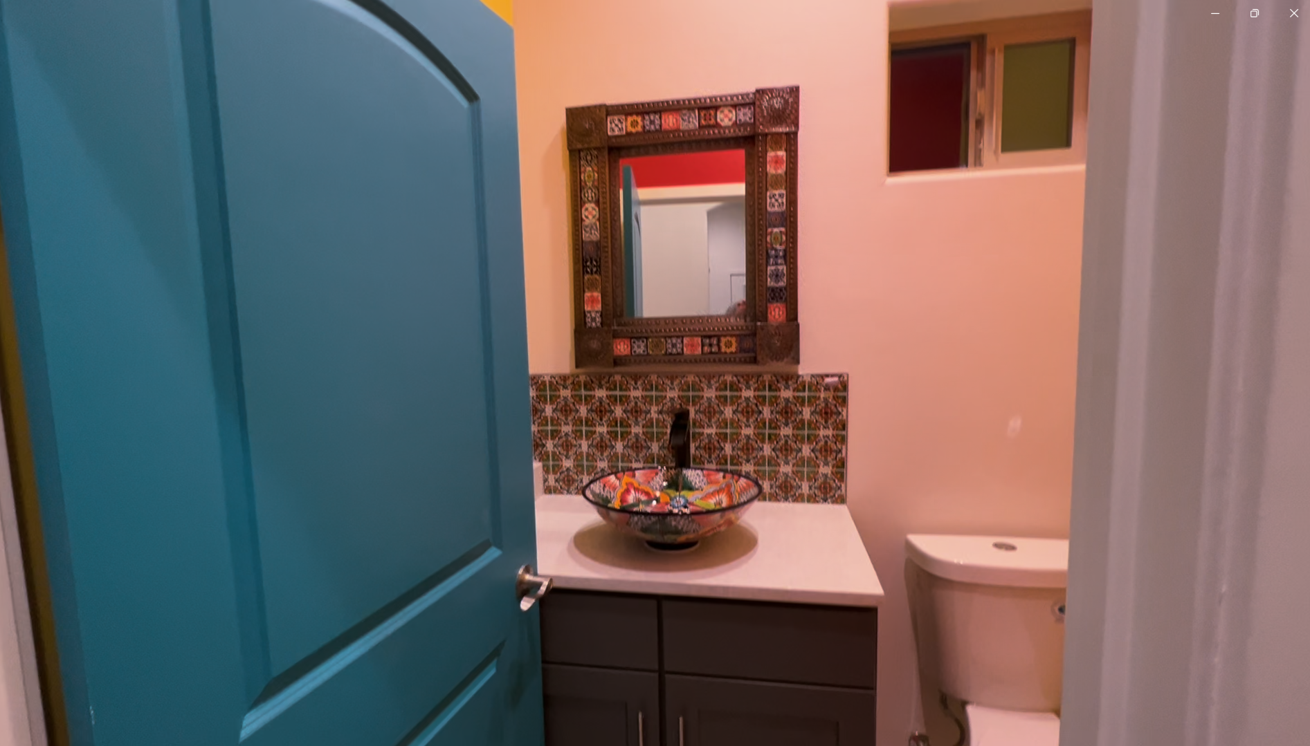 A bathroom with a sink , toilet , mirror and blue door.