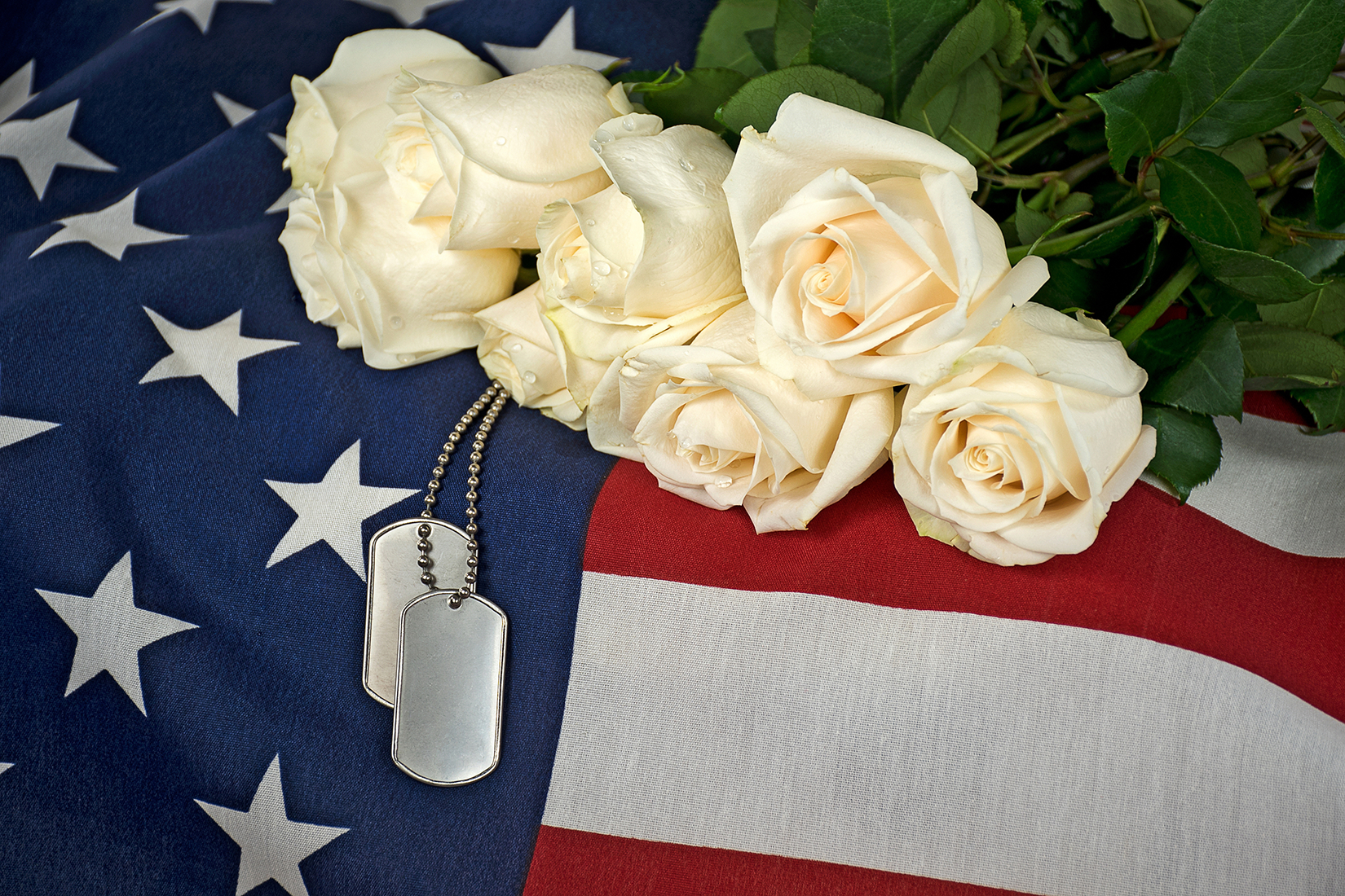 A man in a military uniform is holding an American flag in his hands.