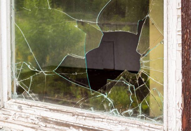 A broken glass window with a hole in it.