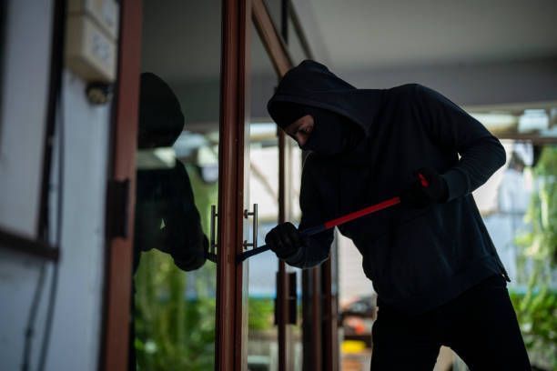 A burglar is trying to break into a house with a crowbar.