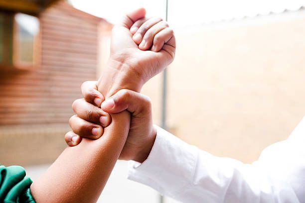 A close up of a person holding another person 's wrist.