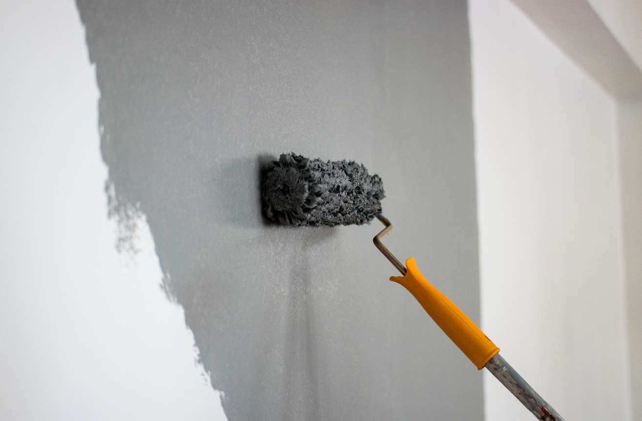 A person is painting a wall with a paint roller.