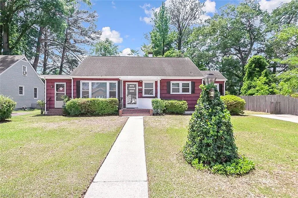 A large house with a wooden roof and a white garage door is surrounded by trees.