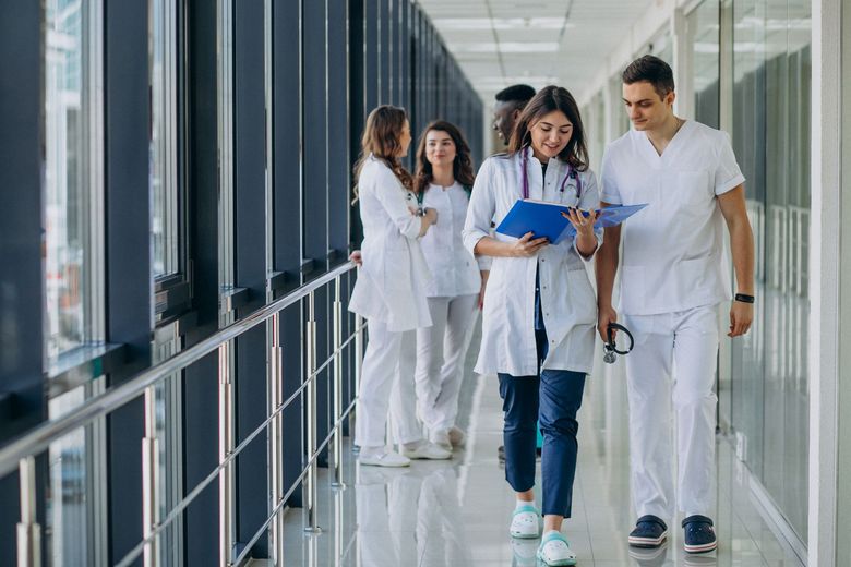 Medical professionals in white coats walking in a hallway, reviewing documents.