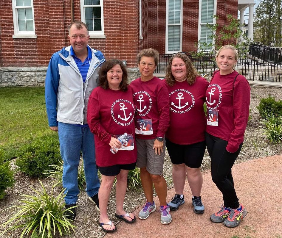A group of people wearing red shirts with anchors on them are posing for a picture.