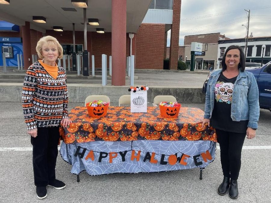 Two women are standing in front of a table decorated for halloween.