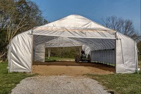 A large white tent is sitting on top of a gravel road.