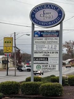 A large sign for insurance incorporated is sitting on the side of a road.
