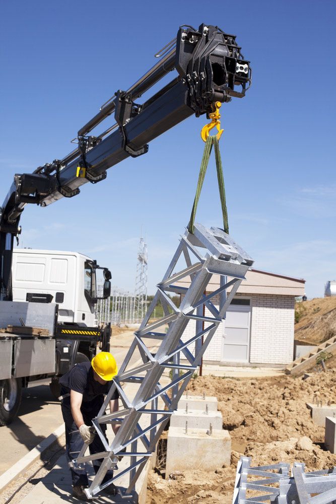 A Man Is Lifting A Metal Structure With A Crane — Gympie Crane Hire In Glanmire, QLD