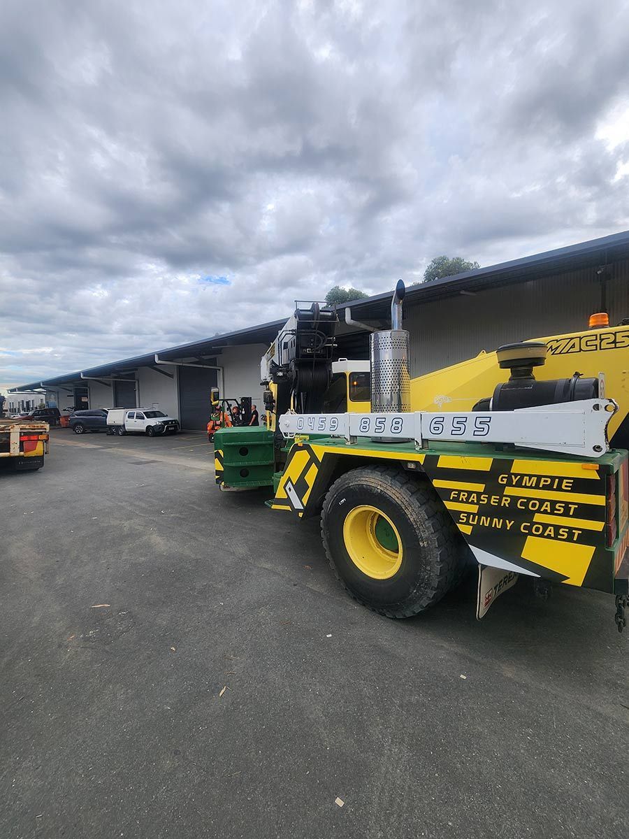 A Yellow And Green Crane Is Parked In A Parking Lot In Front Of A Building — Gympie Crane Hire In Glanmire, QLD