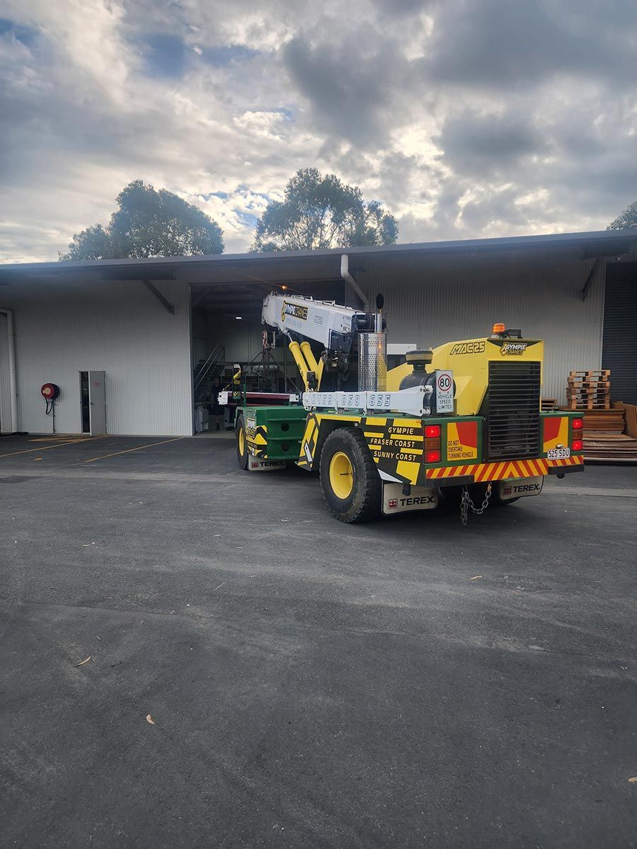 A Yellow And Green Truck Is Parked In Front Of A Building — Gympie Crane Hire In Glanmire, QLD