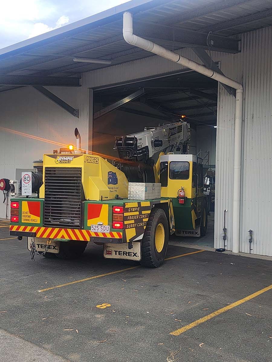 A Yellow And Green Truck Is Parked In Front Of A Building — Gympie Crane Hire In Glanmire, QLD