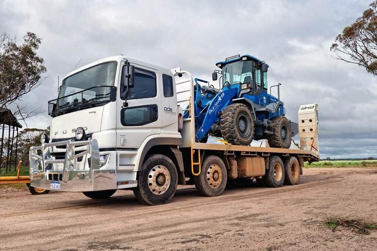A White Truck Is Carrying A Blue Tractor On A Flatbed Trailer — Gympie Crane Hire In Glanmire, QLD