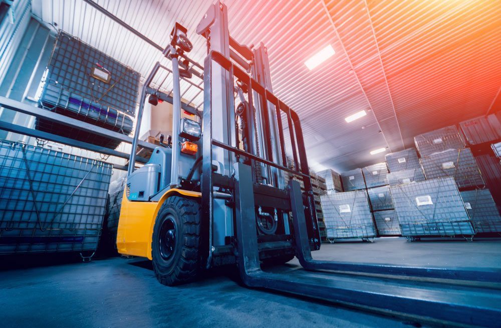 A Forklift Is Driving Through A Warehouse Filled With Lots Of Boxes — Gympie Crane Hire In Glanmire, QLD
