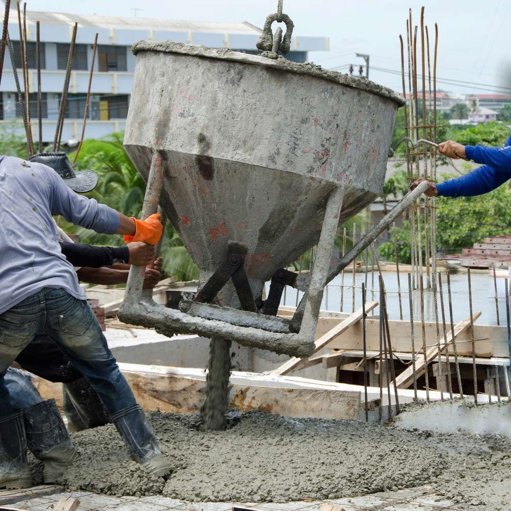 A Group Of Construction Workers Are Pouring Concrete Into A Bucket — Gympie Crane Hire In Glanmire, QLD