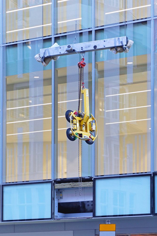A Crane Is Lifting A Glass Window On A Building — Gympie Crane Hire In Glanmire, QLD