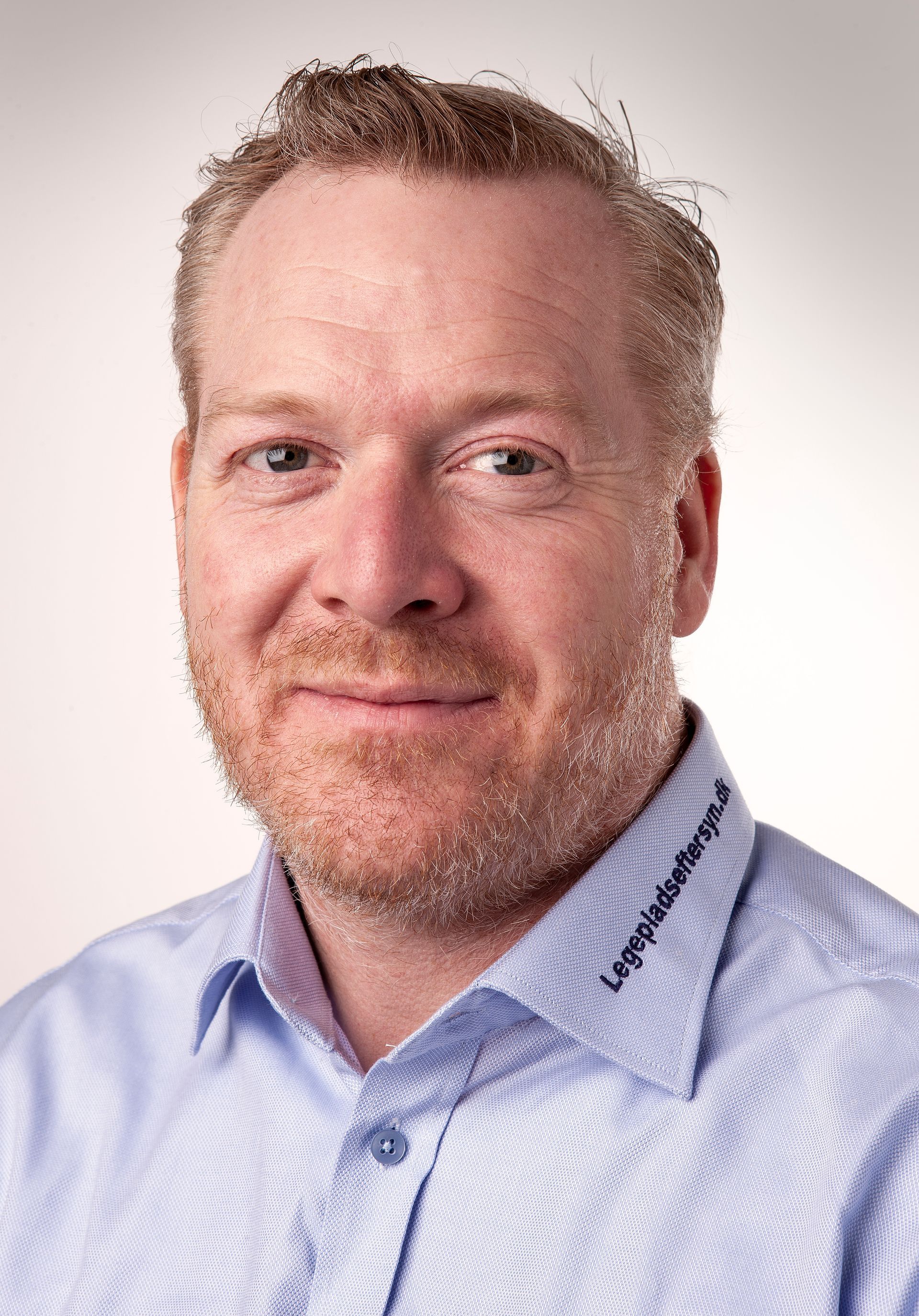 A man with a beard and a blue shirt is smiling for the camera.