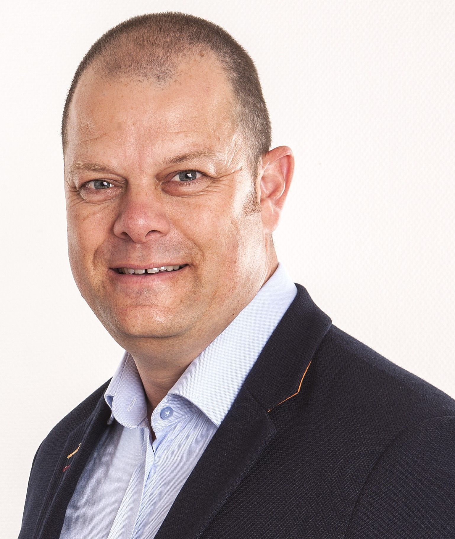 A man in a suit and striped shirt is smiling for the camera.