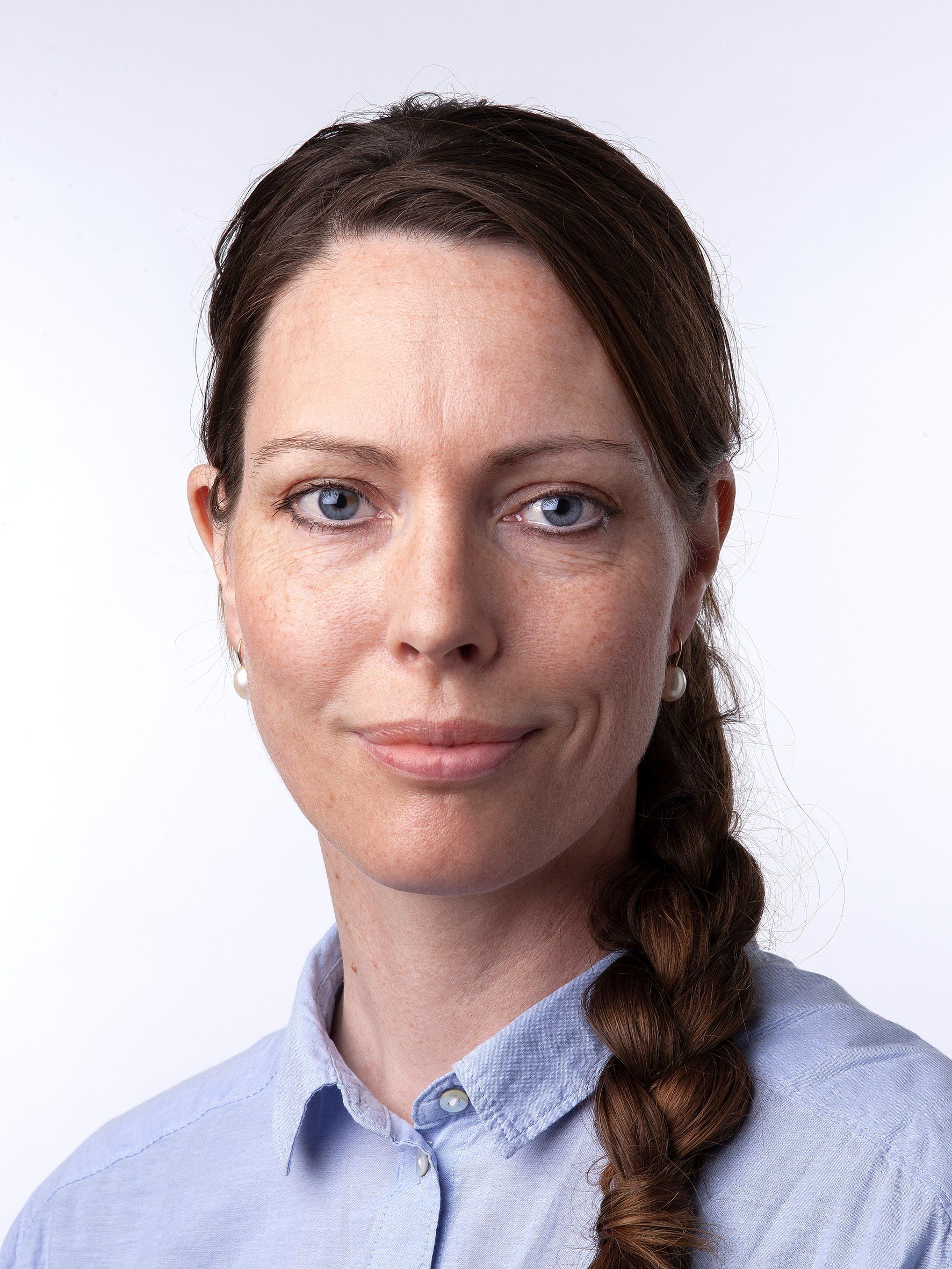 A woman with a braid is wearing a blue shirt and smiling for the camera.