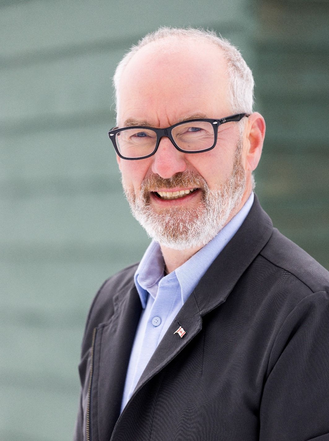 A man with a beard and glasses is wearing a blue shirt.